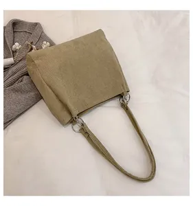 Detailed texture of khaki corduroy tote bag with metal ring strap connection