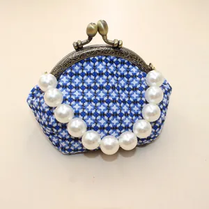 Detail van blauwe geometrische stoffen tas met kus-sluiting en grote witte parels