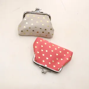 Close-up of gold heart pattern on beige and red fabric coin purses with metal clasps