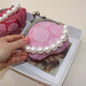 Detail of pink leaf embroidery on vintage canvas kiss-lock purse with pearl handle grip