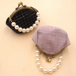 Detail van tweed knipstassen in zwart en lavendel met bronzen sluiting en parelketting