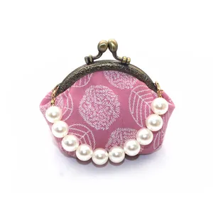 Detail of pink fabric purse with white floral embroidery and elegant pearl handle