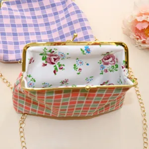 Detail van mini-tas van geruite stof met bloemenvoering en gouden kus-sluiting frame