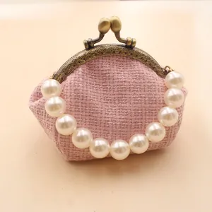 Detail van roze tweed portemonnee met elegante witte parelmoeren handgreep en bronzen frame