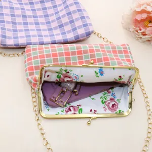 Detail van geruite stoffen crossbodytas met bloemenvoering en metalen clipsluiting