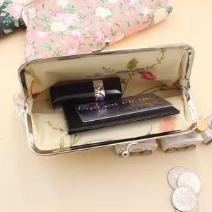 Nahaufnahme der Vintage-Blumenbörse mit Lippenstift und Karten im Inneren