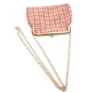 Detail van rood-groene geblokte stoffen tas met goudkleurige sluiting en ketting