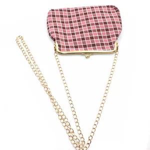 Gedetailleerd zicht op roze-bruin geblokte minitas met gouden ketting en vintage sluiting
