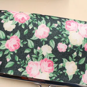 Nahaufnahme der schwarzen Glitzertasche mit rosa Rosenmuster und silbernem Verschluss