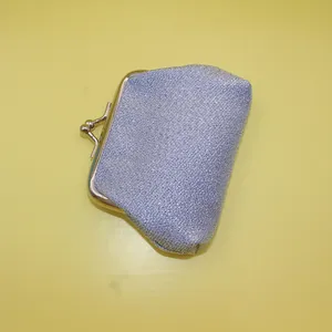 Gros plan sur un porte-monnaie bleu scintillant avec fermoir doré sur fond jaune