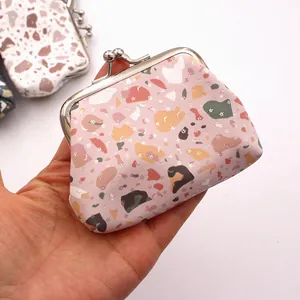 Mini pink terrazzo print coin purse with silver metal clasp held in one hand