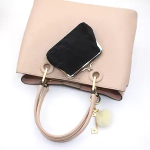 Detail van beige gewatteerde handtas met zwarte fluwelen portemonnee en sterrenhanger
