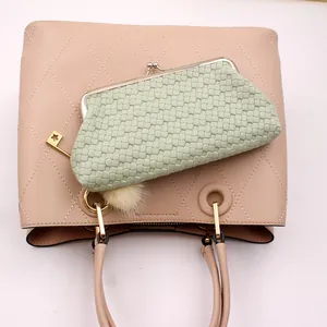 Detailopname van roze gewatteerde tas en groene geweven clutch met bedeltje