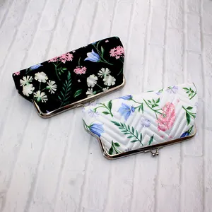 Detail van bloemen portemonnees met metalen framesluiting en V-vormige stiksels