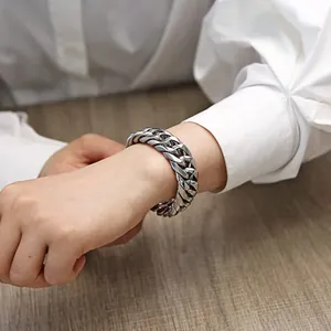 Men's chunky silver titanium steel Cuban link bracelet worn on wrist with white shirt