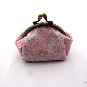 Detailweergave van roze brokaat portemonnee met maneki-neko patronen en bronzen metalen sluiting