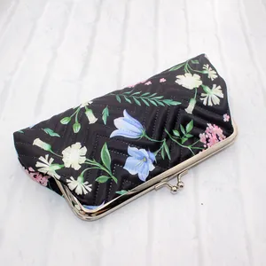 Detail van stoffen portemonnee met bloemenprint, gewatteerd met zilveren metalen sluiting