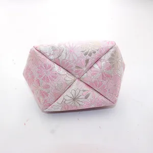 Detail van roze en zilveren bloemenbrokaatstof op een geometrische Japanse muntenzakje
