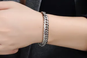 Close-up of polished silver punk cuban chain bracelet on a man wearing a grey suit