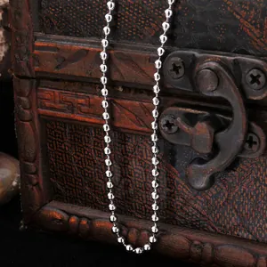 Polished silver beaded metal chain draped over a vintage wooden treasure chest