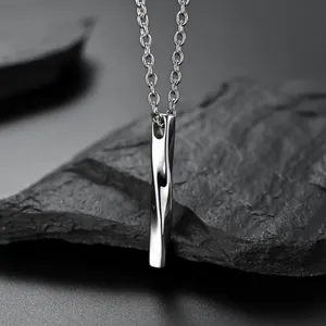 Macro shot of twisted bar pendant on cross chain against a dark textured rock background