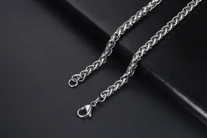 Macro shot of silver wheat chain necklace featuring a lobster clasp on black leather