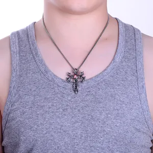 Close-up of men's gothic dragon cross necklace with red gemstone inlay on silver pendant