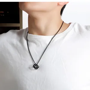 Detailed view of men's black hollow cube pendant on a minimalist steel chain link