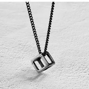 Macro shot of minimalist hollow cube pendant in matte silver steel on black chain