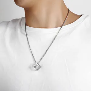 Close-up of men's silver hollow cube pendant necklace worn on a white t-shirt