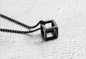 Macro detail of industrial style hollow cube pendant with blackened titanium steel finish