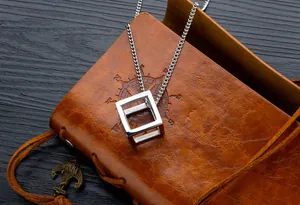 Close-up of a 3D hollow cube pendant on a silver steel chain over vintage leather