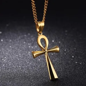 Makro-Detail des polierten gold Ankh-Kreuzanhängers an einer Gliederkette auf schwarzem Grund