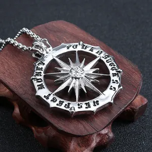 Detailed close-up of a silver compass pendant engraved with Power and Success on wood
