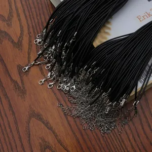 Detail of bulk black wax cord necklaces with silver lobster clasps on a wooden surface