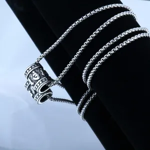 Macro view of vintage silver cylinder pendant with engraved mantra on box chain