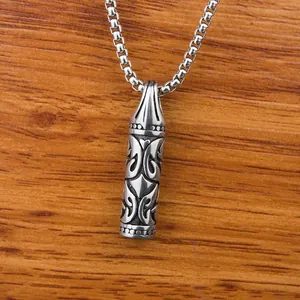 Détail macro du pendentif balle argentée avec gravures tribales sur fond bois