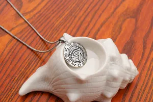 Detail of Eye of Horus engraved round pendant necklace on seashell and wood backdrop