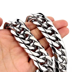 Detailed view of heavy silver polished Cuban link chain held in hand for scale