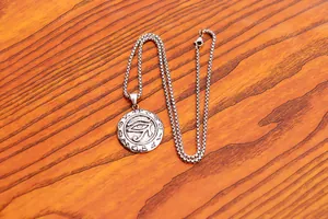 Macro shot of stainless steel Eye of Horus pendant with retro hieroglyphs and box chain