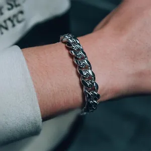 Dettaglio del bracciale a catena cubana in argento lucido sul polso di un uomo
