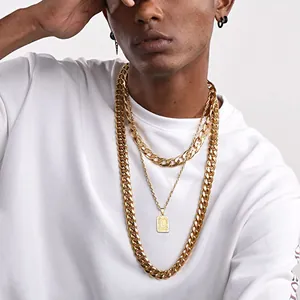 Detailopname van gelaagde gouden Cubaanse ketting en hanger op witte streetwear