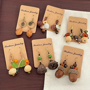 Détail de six paires de boucles d'oreilles vintage en noix et pommes de pin sur bois