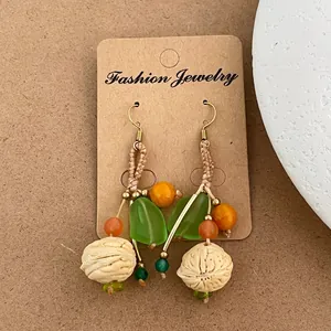 Détail de boucles d'oreilles artisanales avec graines naturelles et pendentifs de feuilles