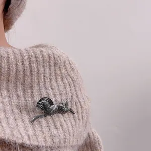 Vintage silver horse brooch for men and women on a beige sweater jacket lapel