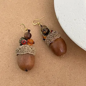 Détail de boucles d'oreilles gland faites main avec texture bois et crochet métal