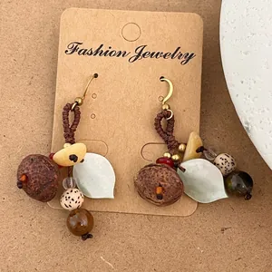 Détail de boucles d'oreilles artisanales forêt avec cordons tressés et coques de noix