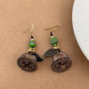 Détail de boucles d'oreilles ethniques avec feuilles dorées et gousses de graines