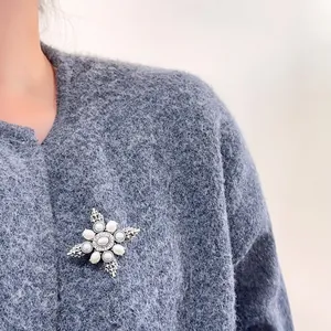 Vintage Baroque cross brooch with pearls on grey wool sweater close-up view