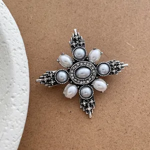 Close-up of vintage silver star brooch with faux pearls and rhinestones on kraft paper